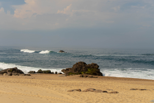 Ocean beach in Madalena, near Porto, Portugal. Yellow sand and lots of big rocks, big waves on atlantic ocean