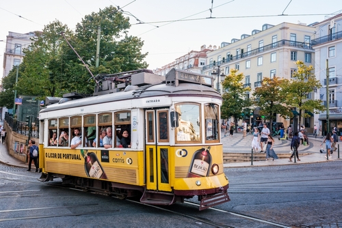 Famous vintage yellow tram 28 in street at the crowded Luis De Camoes square Praca Luis de Camoes, one of the biggest squares in Lisbon city in Portugal